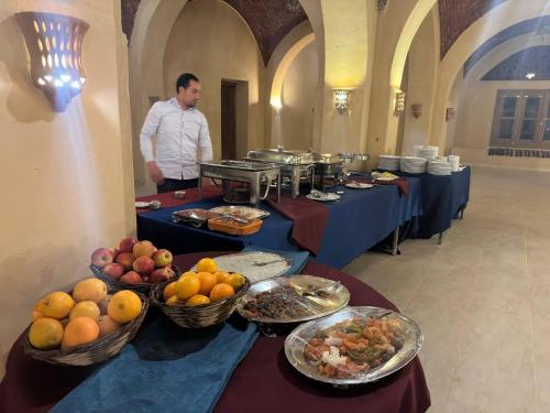 a man standing in front of long tables filled with food at badawiya farafra hotel in Qasr Al Farafirah