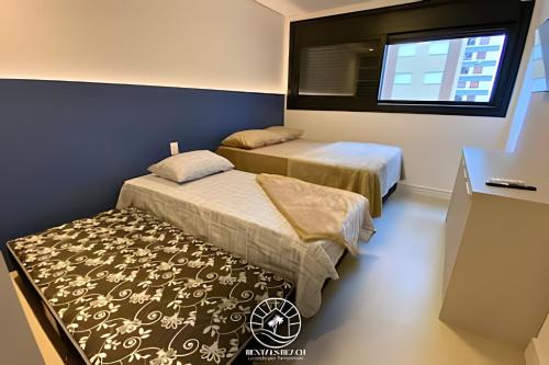 due letti in una stanza con finestra di Apto em Torres - 250m do mar - Ar condicionado e TV smart sala e quartos - Wifi - Churrasqueira - Garagem coberta - Ao lado das Quatro Praças - Aceita Pet a Passo de Torres