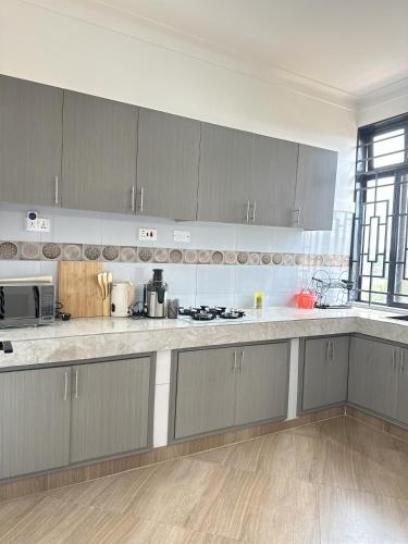 a kitchen with gray cabinets and white counter tops at Zaya Residency in Kampala