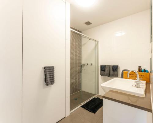 a white bathroom with a sink and a shower at Elegant Apartment, Heart of Newtown with Secure Parking in Sydney