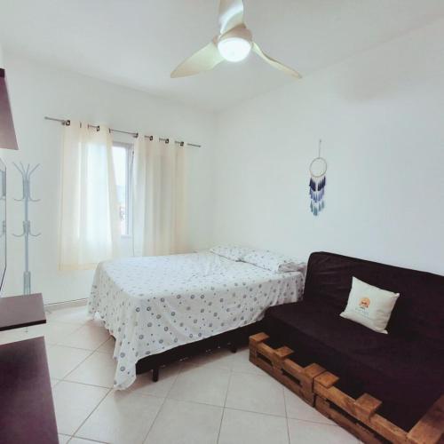 a white bedroom with a bed and a couch at Apartamento Confortável a 350m da Praia dos Sonhos Itanhaém in Itanhaém