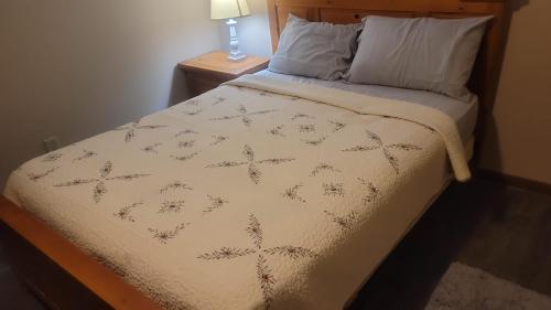 a bed with a white comforter and a lamp on a table at CareHouse Residence in Lawnside
