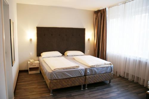 a bedroom with a bed and a large window at Bahn-Hotel in Düsseldorf