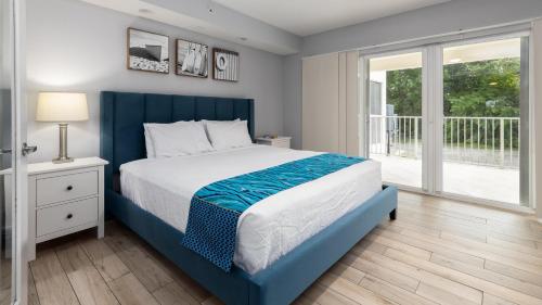 a bedroom with a blue bed and a balcony at 610 Mariners Club in Key Largo