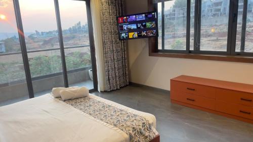 a bedroom with a bed and a dresser and windows at Ved Villa Netflix, Pool, Chill in Panchgani