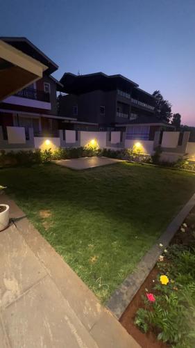 a large yard with a building with lights on at Ved Villa Netflix, Pool, Chill in Panchgani