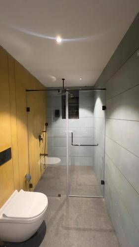 a bathroom with a toilet and a glass shower at Ved Villa Netflix, Pool, Chill in Panchgani