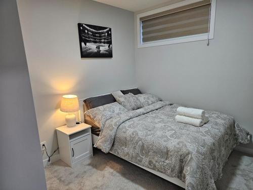 a bedroom with a bed and a lamp and a window at Brand-New Guesthouse-2bedrooms in Calgary