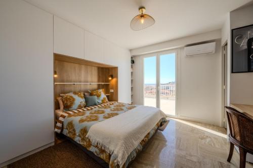 une chambre avec un grand lit et une grande fenêtre dans l'établissement Appartement avec terrasse et vue mer, à Cannes
