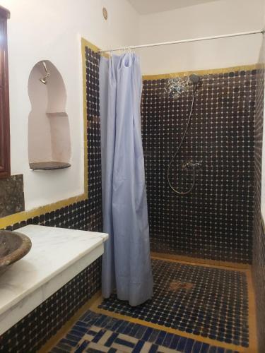 a shower with a blue shower curtain in a bathroom at Sun Palmeraie - Book your Room in Erfoud