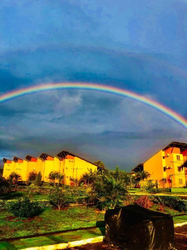 a rainbow in the sky over some houses at Flat Completo 2 Quartos Winterville - Gravatá in Gravatá