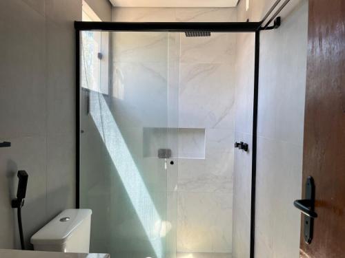 a glass shower in a bathroom with a toilet at Lar da Colina in Maricá