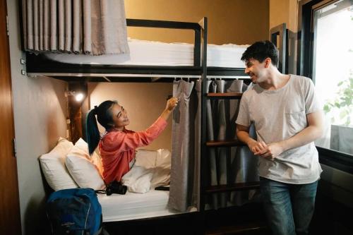 a man and a woman standing in front of a bunk bed at TJ PATONG HOSTEL - Prime Location by OTOP Market & Sea in Patong Beach