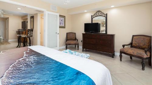 a bedroom with a bed and a tv and chairs at 611 Mariners Club in Key Largo