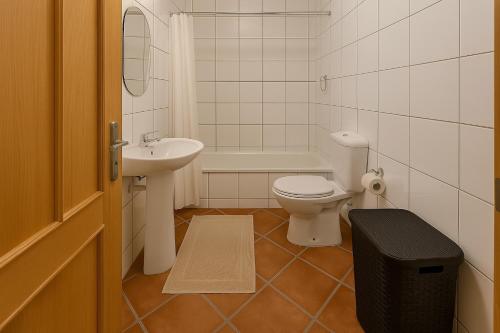 Un baño con inodoro, lavabo y bañera. en Apartamento Centro das Furnas, en Furnas