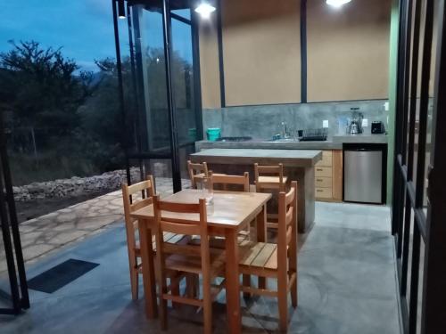 a kitchen with a wooden table and chairs and a window at Bungalow al pie de la montaña in Tlalixtac de Cabrera