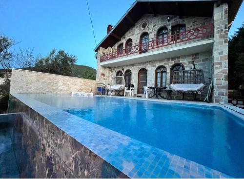 a swimming pool in front of a house at Detached Stone Villa with Pool Sleeps 9 in Burhaniye