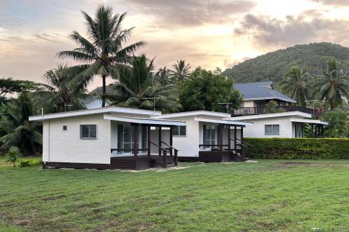 a white house with a palm tree behind it at Muri Serene Villas in Muri
