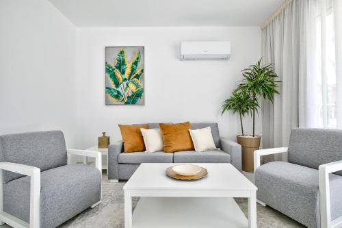 a living room with a couch and two chairs and a table at Aphrodite Gardens Modern Villas by VICHY Holidays in Paphos