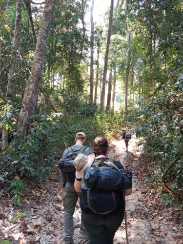 a man and woman walking down a trail in the woods at Tribal Village Homestay & Trekking in Banlung