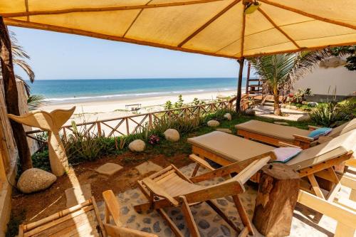 a patio with chairs and an umbrella and the beach at Private Complete Beach House, POOL AC, Vichayito in Vichayito