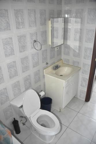 a white bathroom with a toilet and a sink at Embassy Royale in Kingston