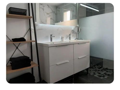 une salle de bain avec un lavabo blanc et un miroir dans l'établissement maison de vacances au calme avec espace jaccuzi, à La Turballe