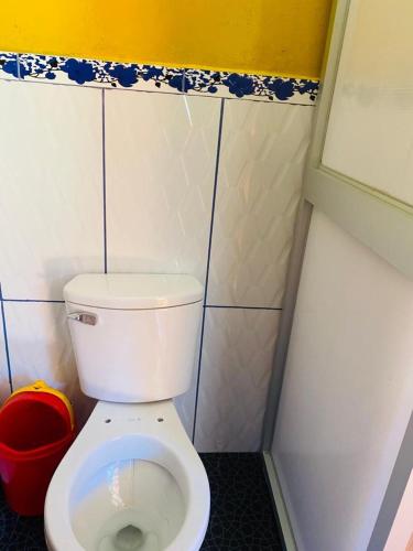 a bathroom with a white toilet in a stall at La HACIENDA LODGE & CAMPING in Santa Teresa