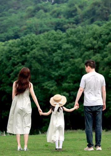 a man and a woman walking in a field with a child at 哲帆民宿花园洋房江与城店 in Chongqing
