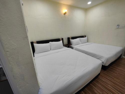 two beds in a room with white sheets and pillows at Reds Roomstay Pantai Penarik 3 in Kampong Ru Sepuloh