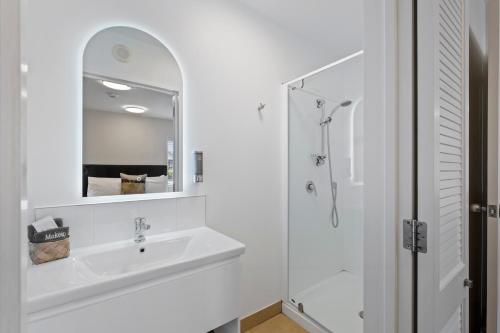 a white bathroom with a sink and a mirror at Tussock Peak Lodge in Hanmer Springs