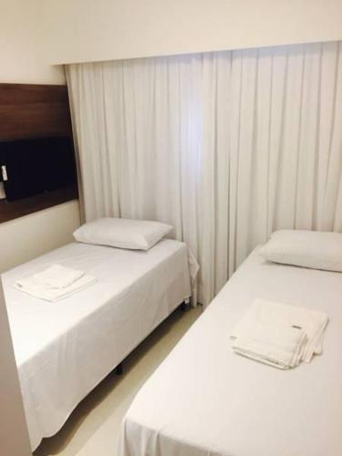 two beds in a hotel room with white curtains at Malawi Resort Experience INN in Porto De Galinhas
