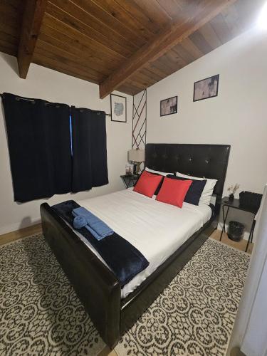a bedroom with a large bed with red pillows at P&N Suites - DELUXE QUEEN ROOM- LONDON in Edmonton