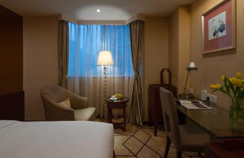 a hotel room with a desk and a bed and a table and chairs at Chengdu Tianfu Sunshine Hotel in Chengdu
