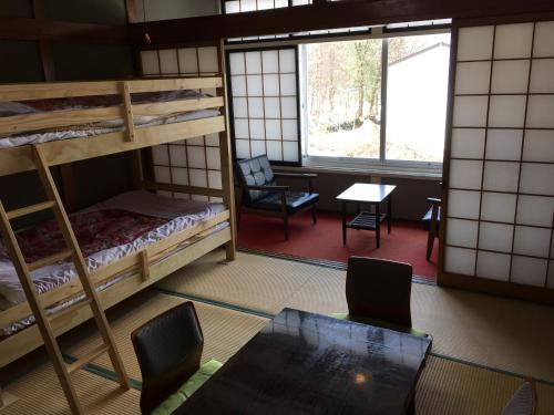 a room with bunk beds and a table and chairs at Towadako Hostel in Towada