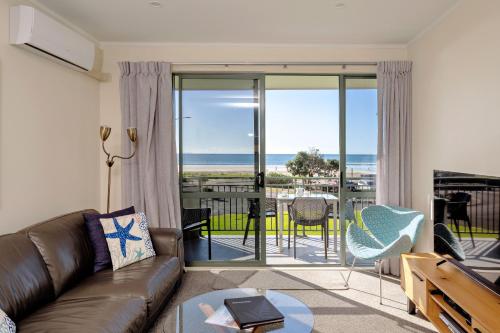 a living room with a couch and a view of the ocean at Beachpoint Apartments in Ohope Beach