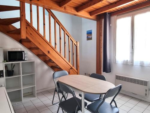une table et des chaises dans une pièce avec un escalier dans l'établissement Appartement en duplex 4 couchages au cœur de Port-Vendres, face à la place de l'Obélisque - FR-1-309-337, à Port-Vendres