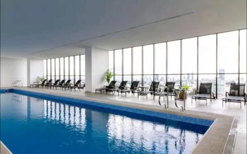 a swimming pool in a building with chairs at Departamento Superior 4H-61 in Guadalajara