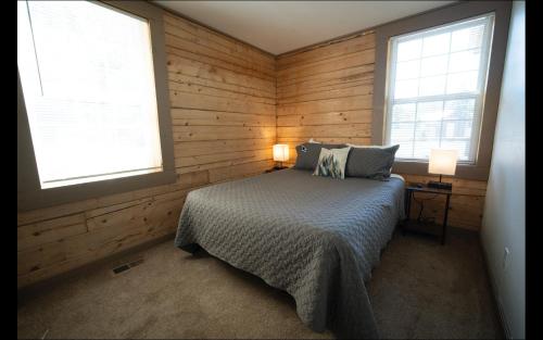 a bedroom with wooden walls and a bed and two windows at Alpine Lodge Hotel in Cascade