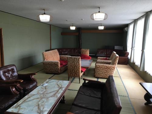 a waiting room with couches and tables and chairs at Towadako Hostel in Towada