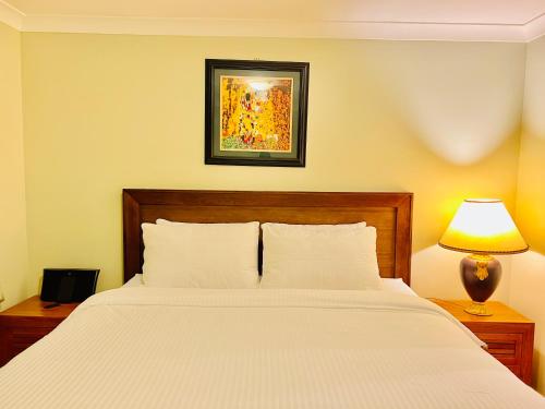 a bedroom with a white bed with a lamp and a picture at An Ensuite Comfort in Sydenham in Sydenham
