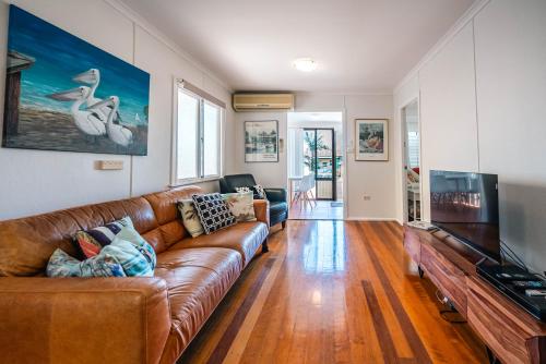 a living room with a brown leather couch and a flat screen tv at The Golden Beach Residence in Golden Beach
