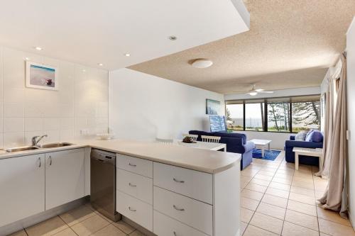 a kitchen with white cabinets and a living room at Bellardoo12- Mooloolaba Beach in Mooloolaba