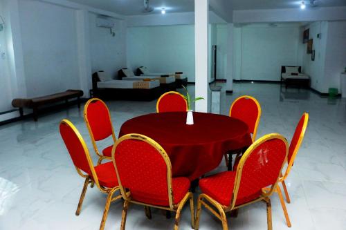 a red table and chairs in a living room at Sea Shine Beach Hotel in Uswetakeiyawa