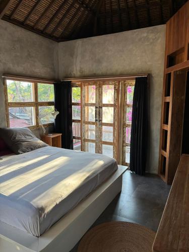 a bedroom with a large bed and some windows at Pink Door Villa Gili Air, private pool & kitchen in Gili Air