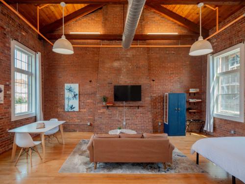 プロビデンスにあるJennifer's Historic Brick Riverfront Loft Apartmentのレンガの壁にリビングルーム(ソファ、テレビ付)