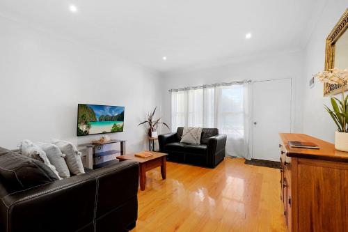 a living room with a black couch and a table at Tuscany in Port Fairy