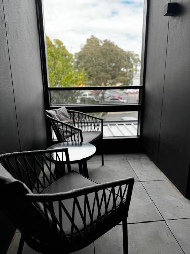 two chairs and a table in front of a window at Brunswick Apartment with Car Park in Melbourne