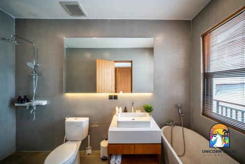une salle de bain avec un lavabo, des toilettes et un miroir dans l'établissement Villa Akarui - by Unicorn Villas Bali, à Tumbak Bayuh