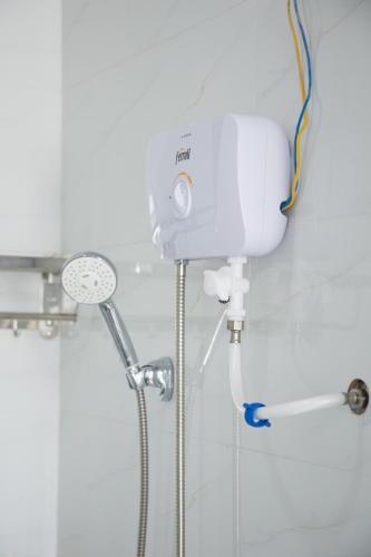 a shower in a white bathroom with a shower at Vicky's House- Balcony Room in Nha Trang